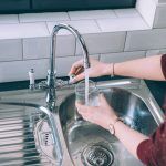 woman filling glass with water from steel faucet kitchen1